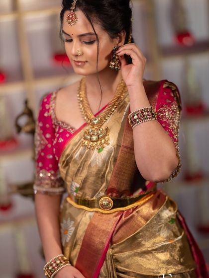 A moment of quiet elegance. The makeup is soft and romantic, with a focus on enhancing her natural features to complement the intricate blouse and timeless South Indian jewellery.