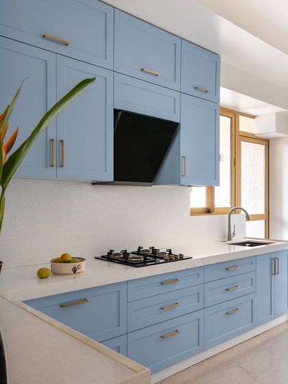 In this kitchen, we used a soft, powder blue for the cabinetry to create a calm and airy feel. The clean lines of the shaker-style cabinets are paired with a simple white countertop and a large window that fills the space with natural light.