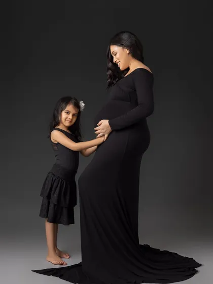 A quiet and tender moment between a mother and her daughter, both connecting with the baby bump.