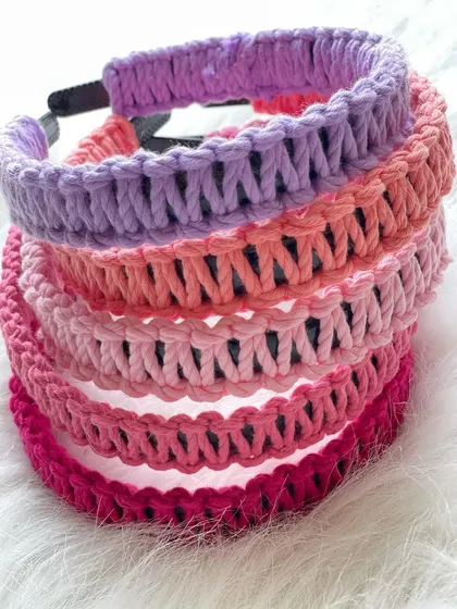 A colorful stack of my macrame hairbands, showcasing a variety of pink and purple shades. I use soft but sturdy cord to ensure they are comfortable enough for all-day wear, for both adults and children.