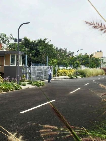 The entrance to a residential layout we planned, featuring a security kiosk and gate. The design is complemented by layered plantings and modern street lighting, establishing a safe and aesthetically pleasing entry point for the community.