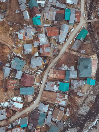 An aerial photograph of a village with colorful rooftops. The drone's perspective turns a simple settlement into a beautiful, abstract pattern.