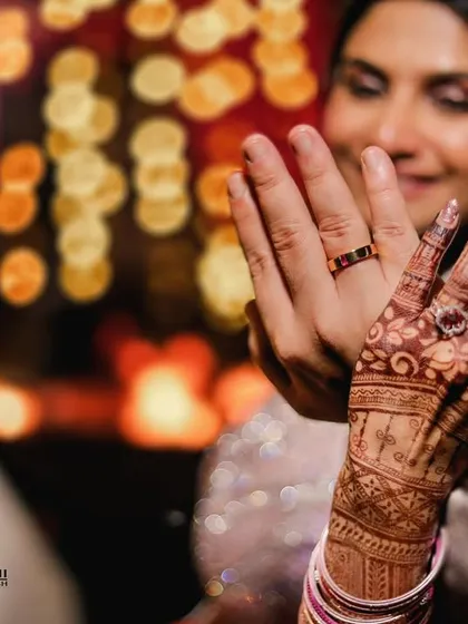 A close-up shot of the couple's hands, showcasing their wedding rings and the bride's intricate henna. This detail shot was taken during their destination wedding at Triyuginarayan.