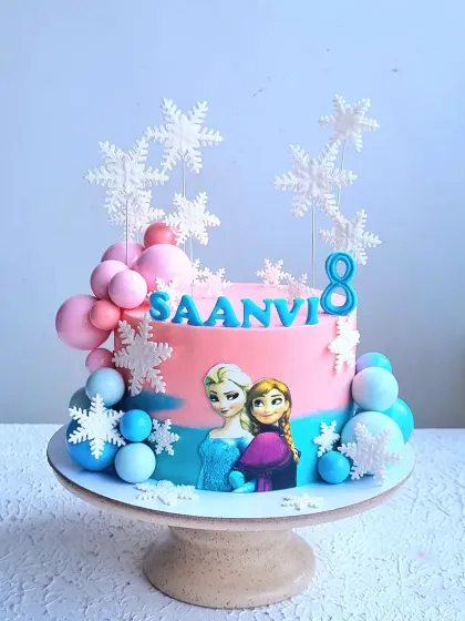 A full view of the pink and blue Frozen cake on its stand.