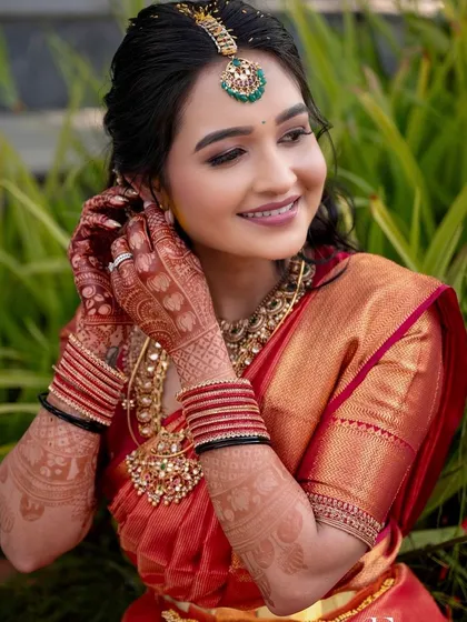 A bride dressed for her Varapooja ceremony in a classic red and gold Kanchipuram saree. The simple, elegant embroidery on her blouse complements the richness of the silk and antique jewelry.