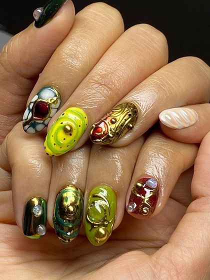 A full view of a truly fantastical nail art set. Each nail is a unique piece of art, combining vibrant colors, metallic gold, and 3D sculpted shapes.