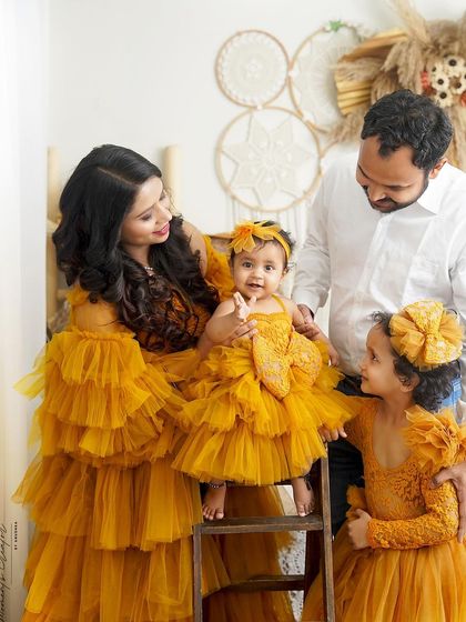 A family portrait glowing with warmth. The mother, father, and two daughters are all dressed in stunning matching yellow outfits, creating a vibrant and happy image.