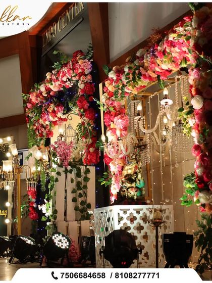 A lavish Sangeet ceremony entrance with a floral arch, lush greenery, and a grand chandelier. The dramatic lighting sets a glamorous tone for the evening.
