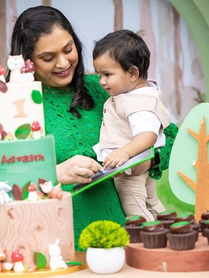 A heartwarming moment at Advaith's woodland party, with his mother showing him the beautiful themed cake.