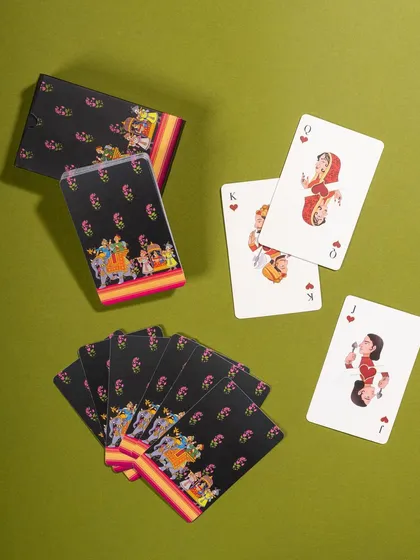 A top-down shot of playing cards with a vibrant, folk-art inspired design. The arrangement shows the front, back, and box, giving a complete view of the product.