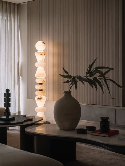 A detail shot of the living room, focusing on the custom stone lamp and the organic, handmade pottery that adds a touch of soul to the space.