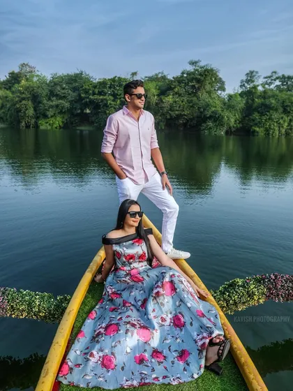 A stylish couple poses in a boat, framed by the lush landscape. This pre-wedding photo has a relaxed, vacation-like feel.
