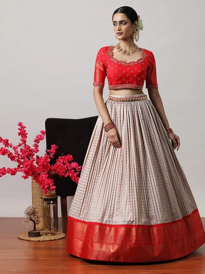 A classic combination of a red embroidered blouse with a beige and red Banarasi border lehenga. This is a timeless choice for any festive occasion.