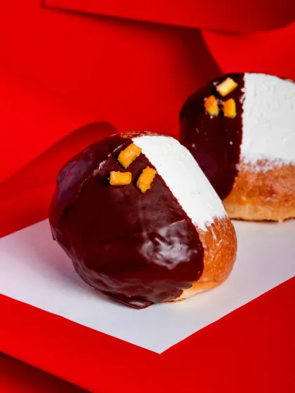 A close-up shot of the Dark Chocolate Orange Maritozzo, highlighting the glossy finish and candied orange garnish.