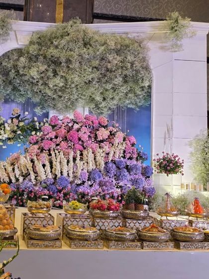 A dreamy stage design with white architectural arches and large mounds of pastel-colored hydrangeas and roses. The baby's breath 'trees' add a touch of whimsy.
