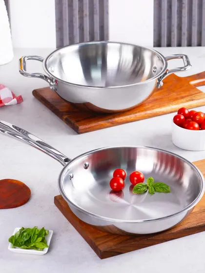 A clean, bright shot of Omichef's stainless steel cookware set. The simple styling with fresh ingredients like tomatoes and basil suggests a fresh cooking experience.