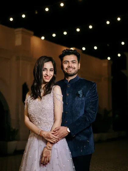 A classic couple portrait taken at night, with the warm glow of overhead lights creating a romantic and sophisticated ambiance.