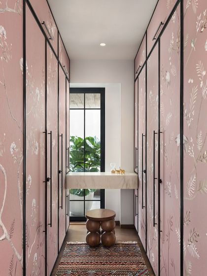 This walk-in closet in the West Coast Residence features custom wardrobe doors with a delicate, hand-painted floral pattern, turning a functional space into a beautiful design moment.