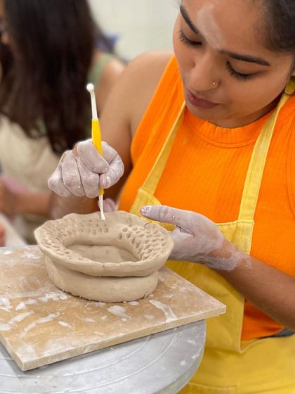 This student is using piercing techniques to create a beautiful, lace-like pattern on the rim of their bowl.