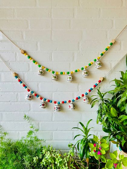Our 'Khanak' beaded bell buntings are perfect for adding a touch of elegance to any space. This image shows two buntings in different color combinations, ideal for doorways or temple spaces.