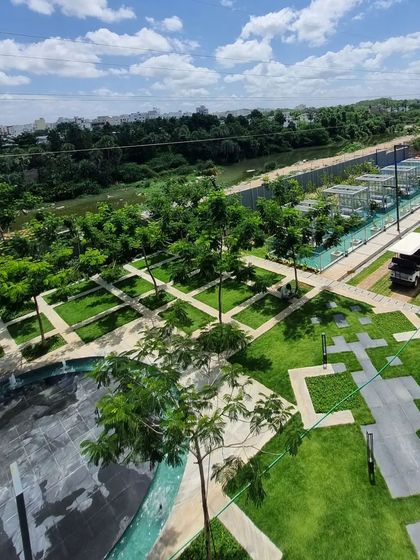 A sneak peek from above at a large residential landscape in Hyderabad. The design uses a geometric pattern of pathways and lawns, interspersed with trees and water features, to create a dynamic and expansive green space.