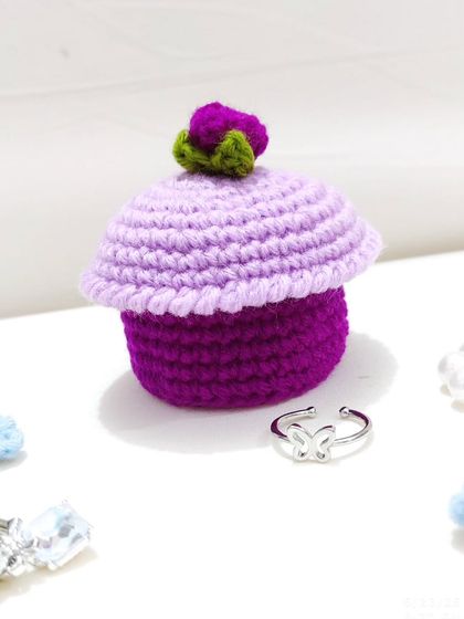 A side view of the cupcake ring box next to a butterfly ring.