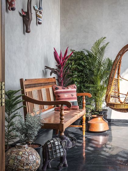 This beautiful balcony adjoining the master bedroom has a calming vibe. A traditional teak bench, a cane swing, and handpicked antique Indian artifacts create a space that speaks of a fondness for ethnicity, floored with local black Cuddapah stone.