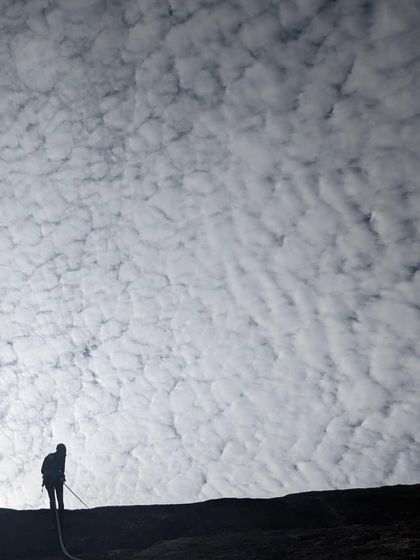 A beautiful, moody shot of a climber rappelling at dusk. The work of route development often continues from dawn till dusk.