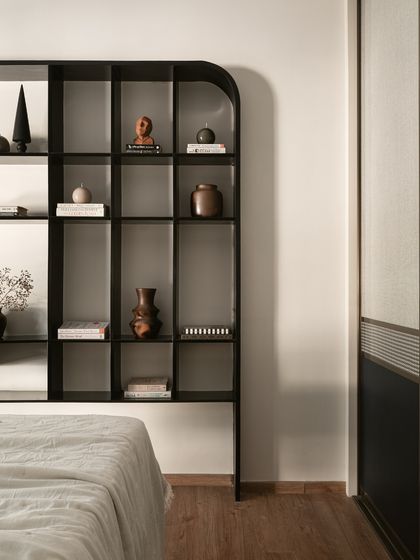 A close-up of the son's bedroom, showing the statement bookshelf in bold black. Its clean lines and curved corner provide ample space for books and decor, blending function with modern design.