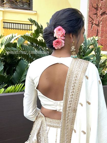 A soft, romantic updo adorned with two pink roses. This simple and elegant style is perfect for a daytime wedding or an engagement party.