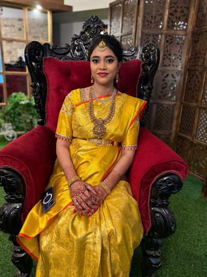 A full view of the baby shower makeover. The bright yellow saree and traditional gold jewellery are perfectly complemented by the classic makeup look.