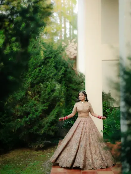 A full-length portrait of the bride in her gorgeous pastel lehenga, twirling in a garden.