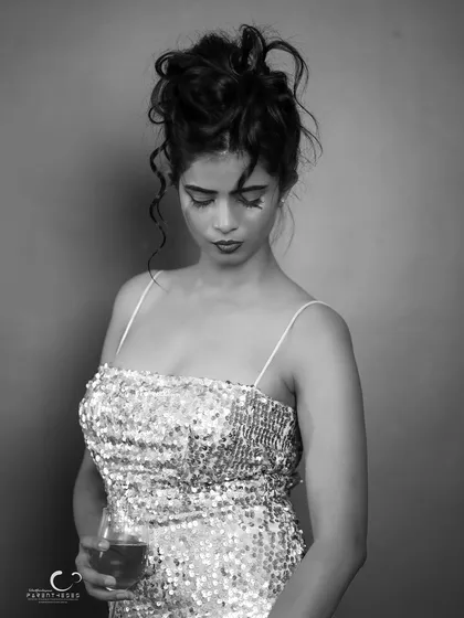A sophisticated and moody black and white portrait. The sequin dress and wine glass create a sense of after-hours glamour and introspection.