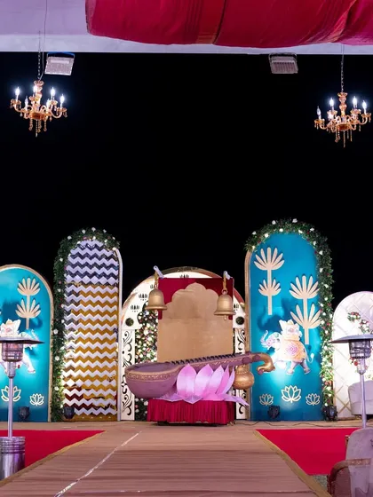 The full stage setup for the Radha-Krishna themed event, featuring a veena and lotus seating area against a backdrop of traditional motifs and vibrant colors.