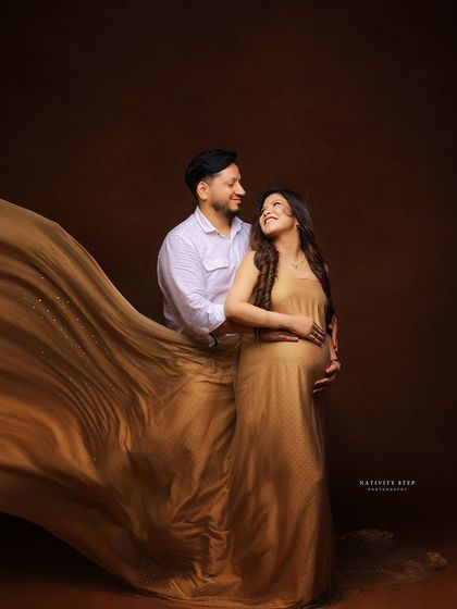 A romantic couple's portrait, wrapped in a flowing golden fabric. This shot emphasizes their connection and the shared magic of the moment.