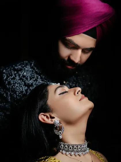 A dramatic, low-key portrait focusing on the bride-to-be's elegant profile and traditional jewelry, with her partner looking on. This highlights our skill in creative lighting.