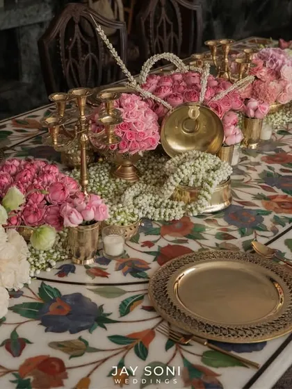 The beauty of an event is in its details. For this intimate dinner, I curated a tablescape with dense pink floral arrangements, traditional gold serveware, and delicate jasmine garlands, all set against a stunning marble inlay table.