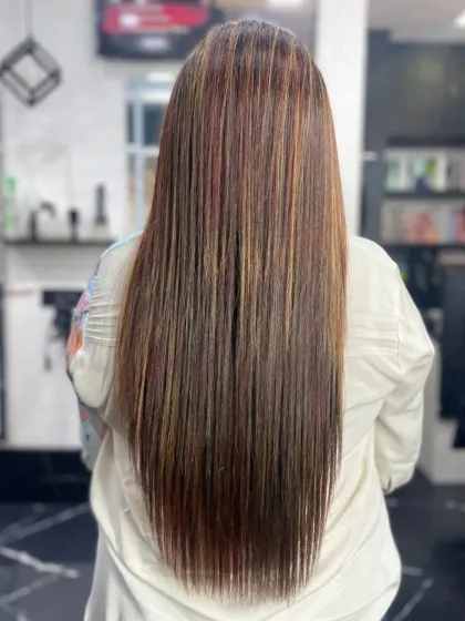 Long, straight hair with expertly blended highlights. This look was achieved with a combination of a global color base, precise highlights, and a final straightening service for that polished finish.