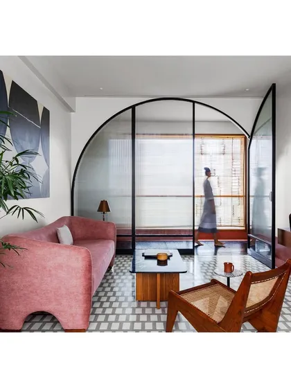 In this lounge, I used a bold color palette and a custom arched glass screen to define the space while maintaining a sense of openness. The design balances modern art with classic materials for a home that feels both exciting and comfortable.