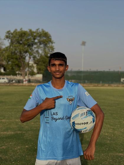 A player proudly points to the club badge on his jersey while holding a football. This is what it means to play for Frontier FC.