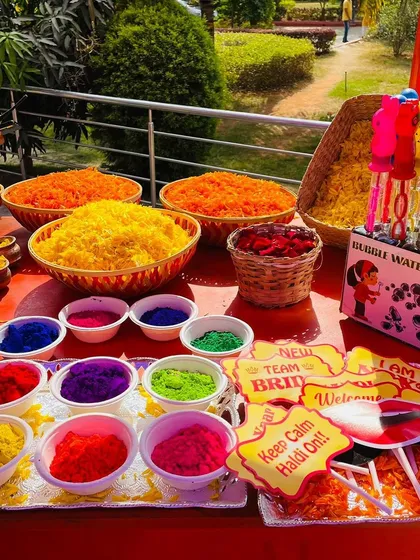 A vibrant station with Haldi powders, flower petals, and fun photo props for guests.