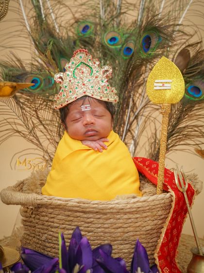 A beautiful portrait of the newborn as Lord Murugan, set against a backdrop of peacock feathers. The details are carefully crafted to honor the theme.