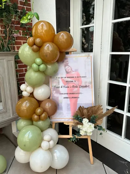 We create personalized welcome signs that match the event's theme. This one, framed by a matching balloon garland, warmly greets guests to the baby sprinkle.
