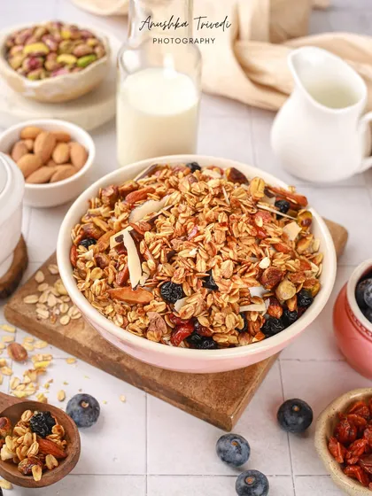 A bright and airy shot of a bowl of granola, surrounded by its ingredients. This type of "deconstructed" shot is great for showing the quality and variety of what's in the product.