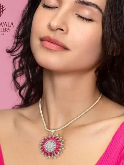 A model wears a striking pendant necklace with a sunburst design of rubies and diamonds.