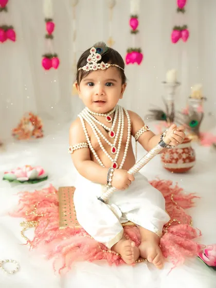 A classic portrait of a baby Krishna holding his flute. The attention to detail in the costume and props makes these themed sessions truly special.