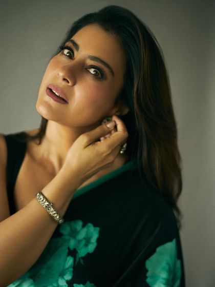 A candid moment adjusting an earring, giving a glimpse of the intricate jewelry chosen for this look.