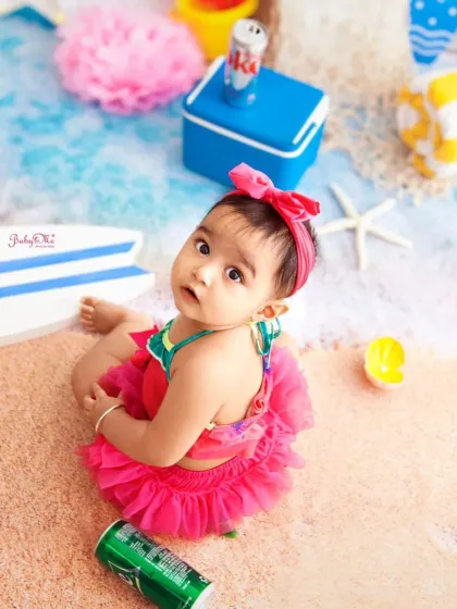 A sweet look from our little mermaid. The high-angle view shows off the entire beach setup, from the sand to the ocean backdrop.