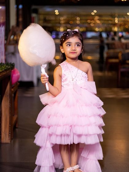 The birthday girl looking chic with a stick of cotton candy, a classic party treat that adds to the fun.