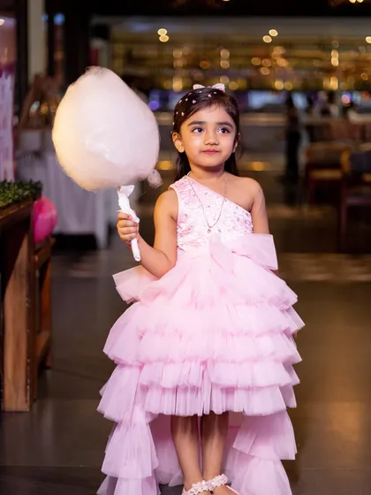 The birthday girl looking chic with a stick of cotton candy, a classic party treat that adds to the fun.